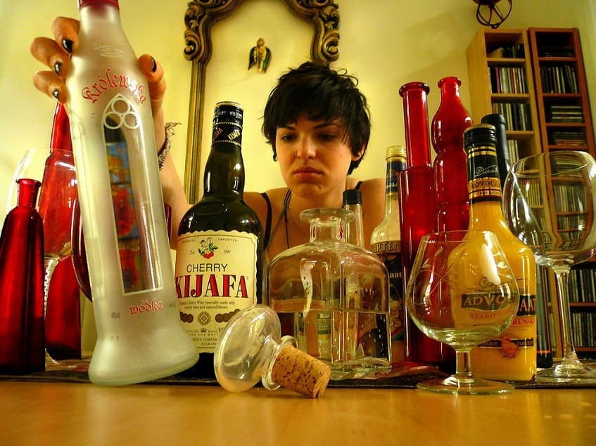 Девушка выбирает бутылку с алкоголем